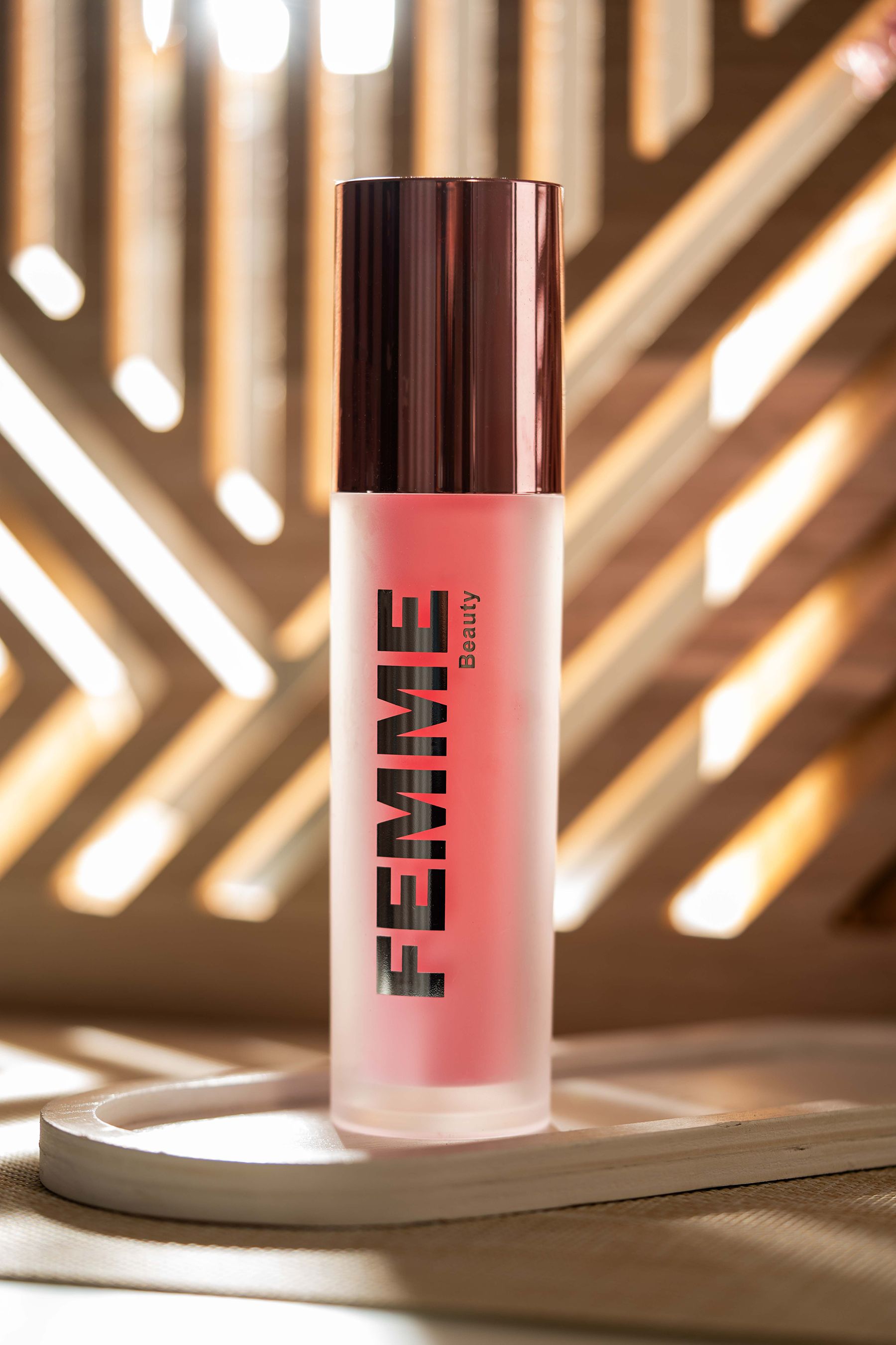 Flasche mit mattem Finish und rosafarbenem Inhalt, roségoldfarbener Verschluss. Marke: FEMME Beauty.
