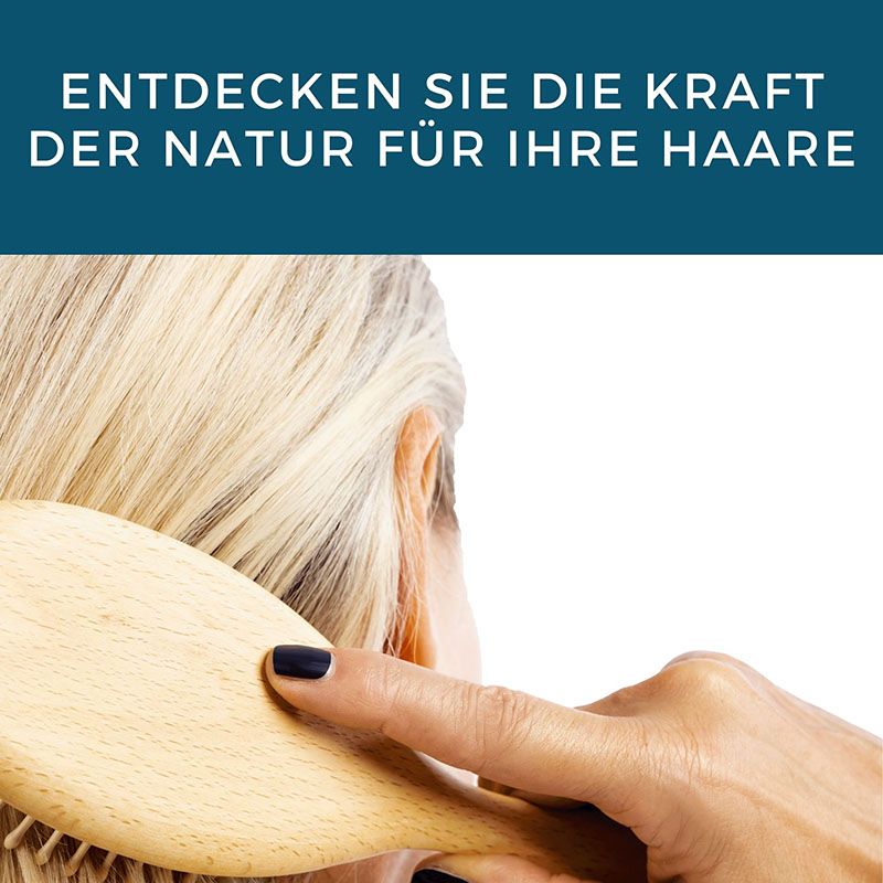 Eine Frau kämmt sich mit einer Holzbürste die Haare. Text: Entdecken Sie die Kraft der Natur für Ihre Haare.