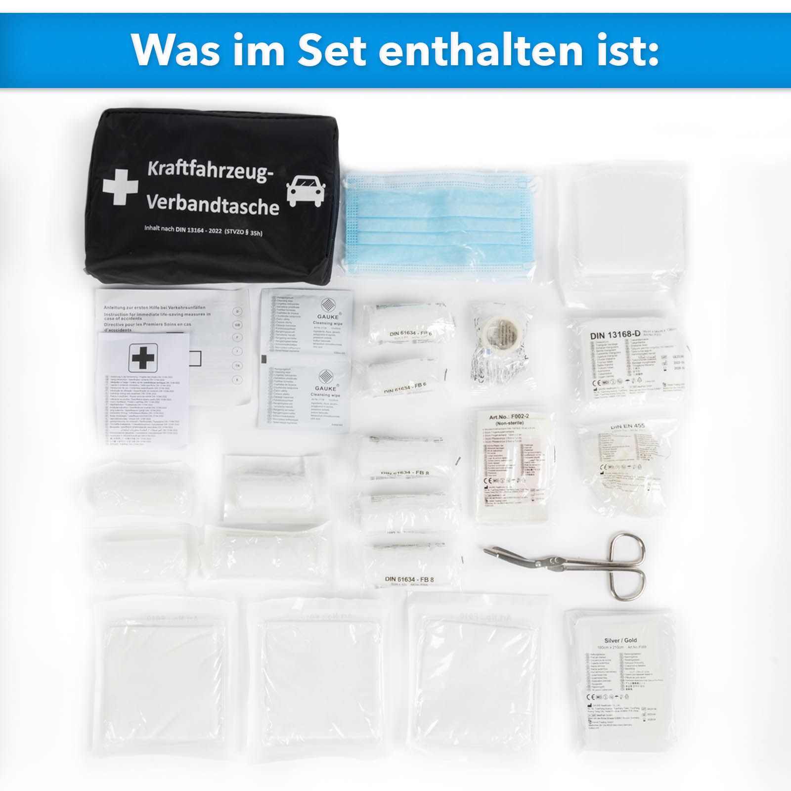 Inhalt der KFZ-Verbandtasche, ausgebreitet. Enthält Verbandsmaterial, Schere und Masken.