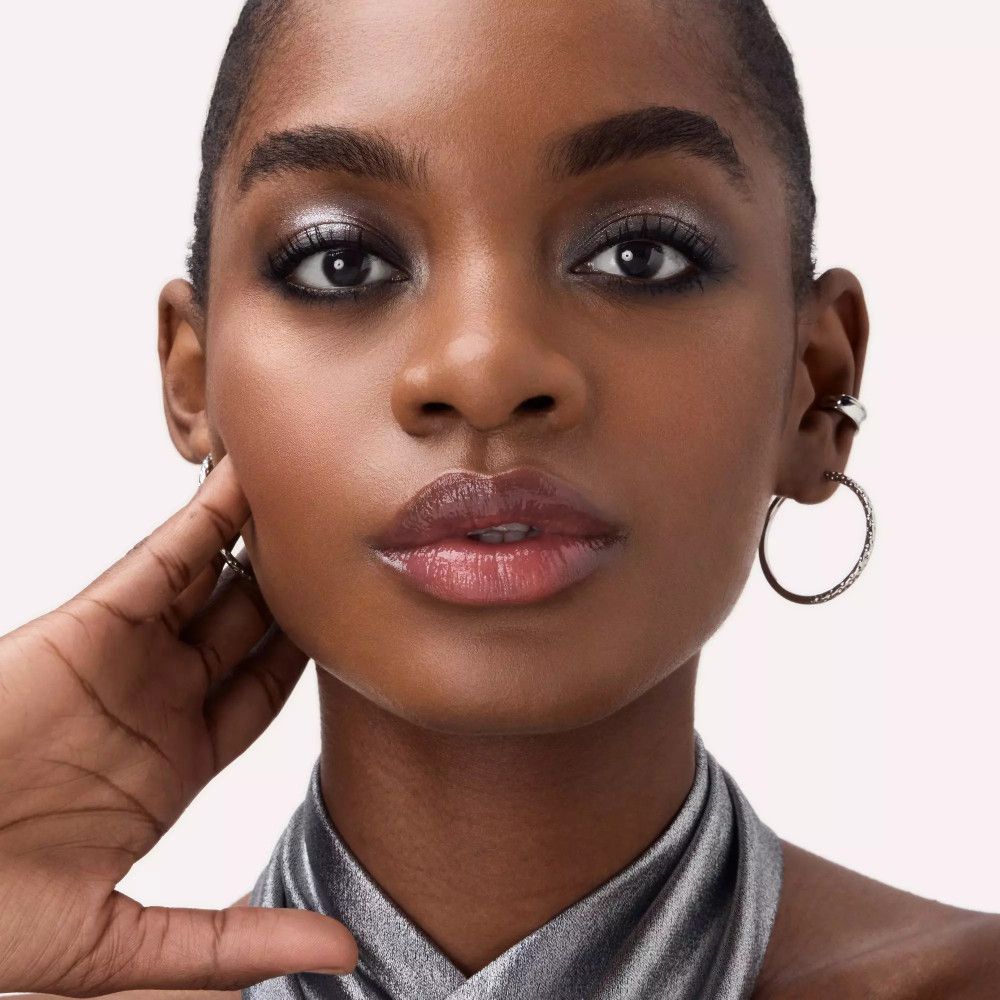 Nahaufnahme eines geschminkten Gesichts. Lidschatten und Lippenstift sichtbar. Hautton dunkel.