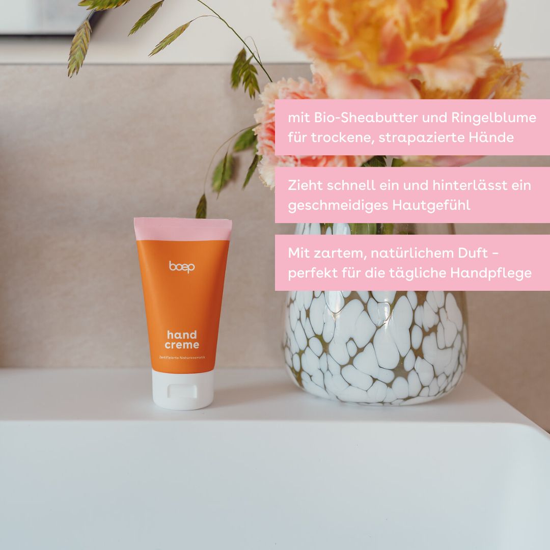 Orange Tube mit rosa Deckel. Aufschrift: boep, hand creme. Steht auf einer weißen Oberfläche.