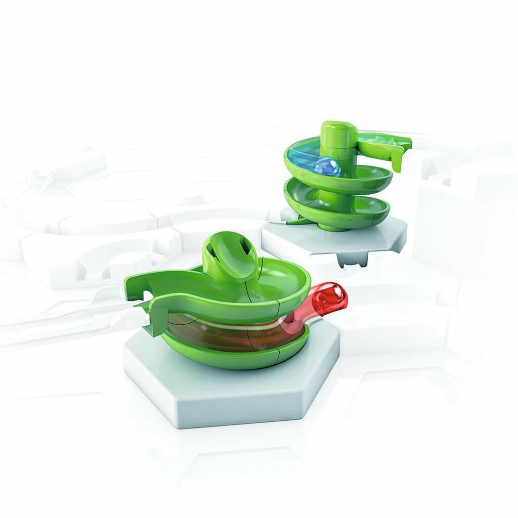 Zwei grüne Spiralen und eine Schiene auf weißen sechseckigen Sockeln. Mehrere grüne Elemente. Kugeln in den Spiralen. Helles Hintergrund.