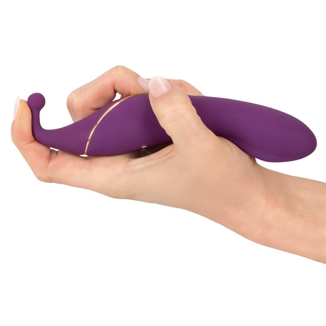 Lila Vibrator in einer Hand gehalten. Geschwungene Form, goldfarbene Akzente. Tropfenförmiger Kopf.
