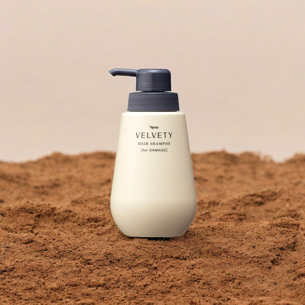 Beige Shampooflasche mit Pumpe auf braunem Untergrund. Schwarzer Schriftzug: VELVETY HAIR SHAMPOO [for DAMAGE].