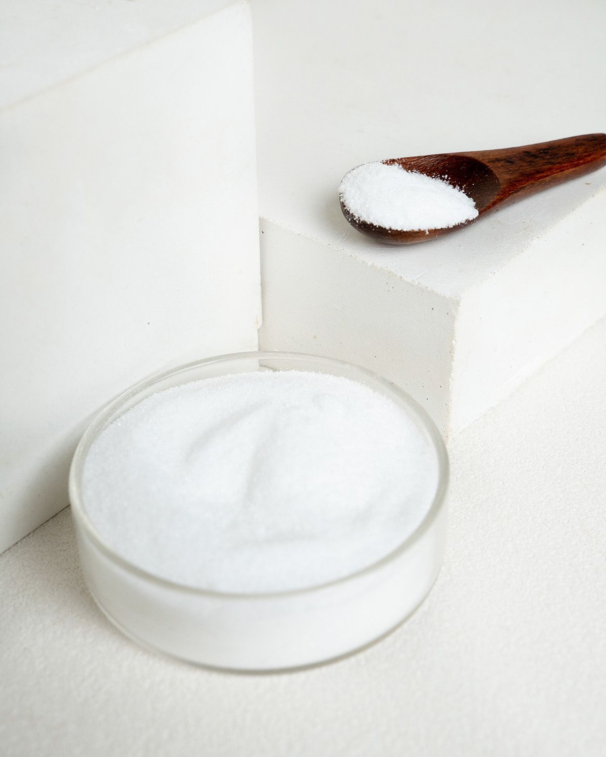 Glucosamin HCL Pulver in einer Petrischale und auf einem Holzlöffel.