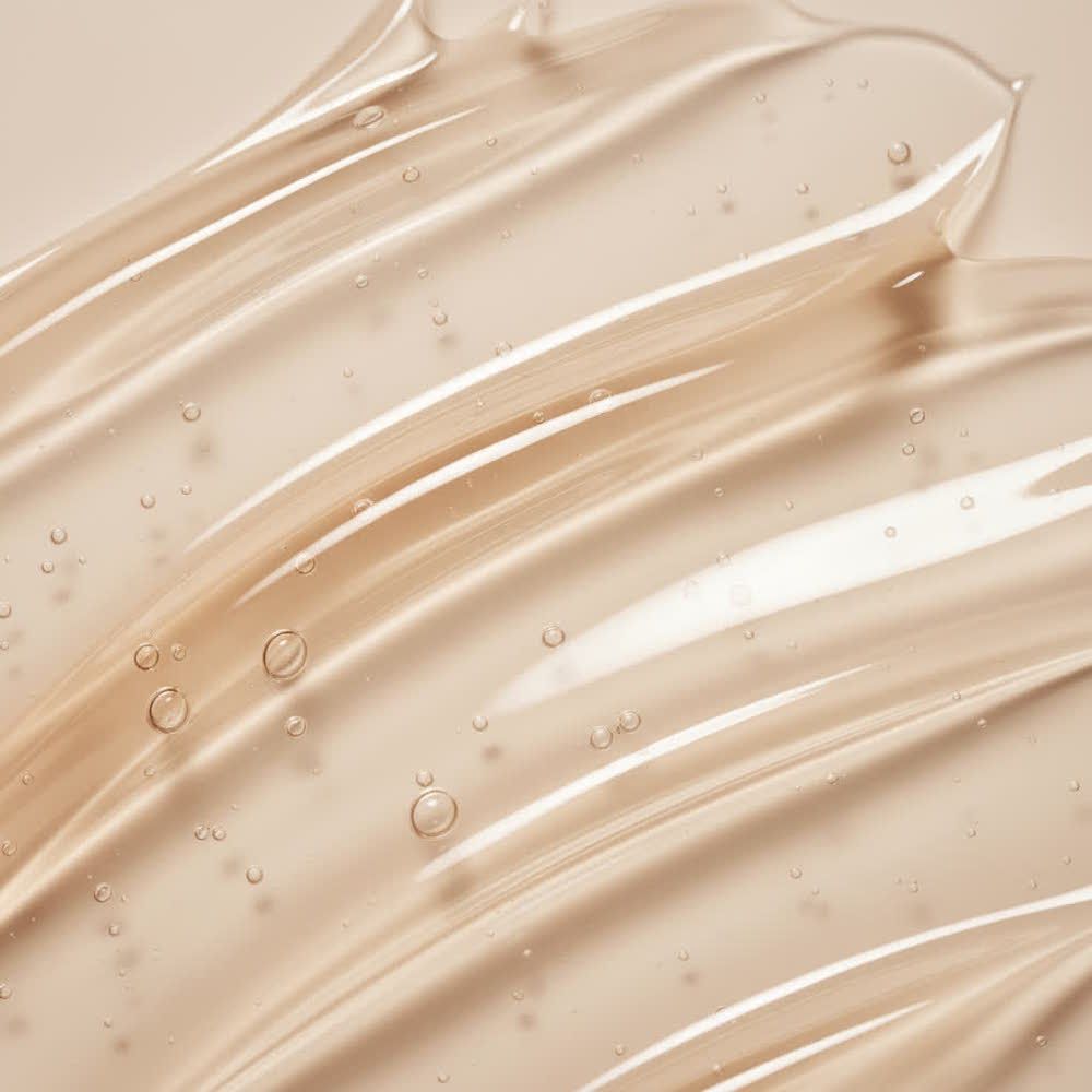 Nahaufnahme von transparentem Gel mit Bläschen. Gel ist in wellenförmigen Bahnen auf hellem Hintergrund aufgetragen.