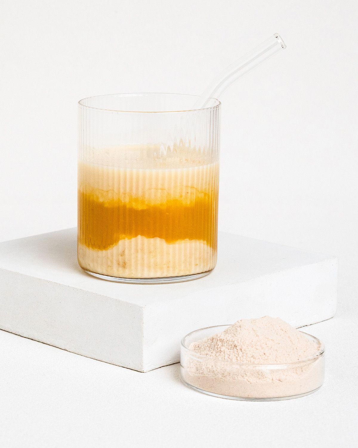 Glas mit Flüssigkeit und Schale mit Flohsamenschalenpulver. Flüssigkeit geschichtet, mit Strohhalm.