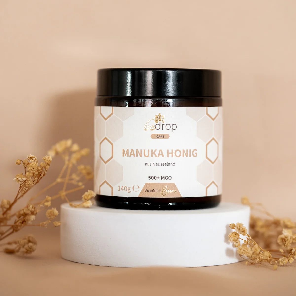 Glas Manuka Honig auf Podest. Etikett mit Produktinformationen. Dekoration mit Zweigen.