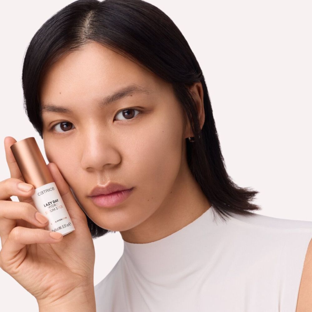 Frau hält einen Serum-Stick. Aufschrift: Catrice, Lazy Day Hydro Serum Stick. Ultra Hydrating. 9g/Net Wt. 0.31 oz e. Roségoldfarbener Deckel.