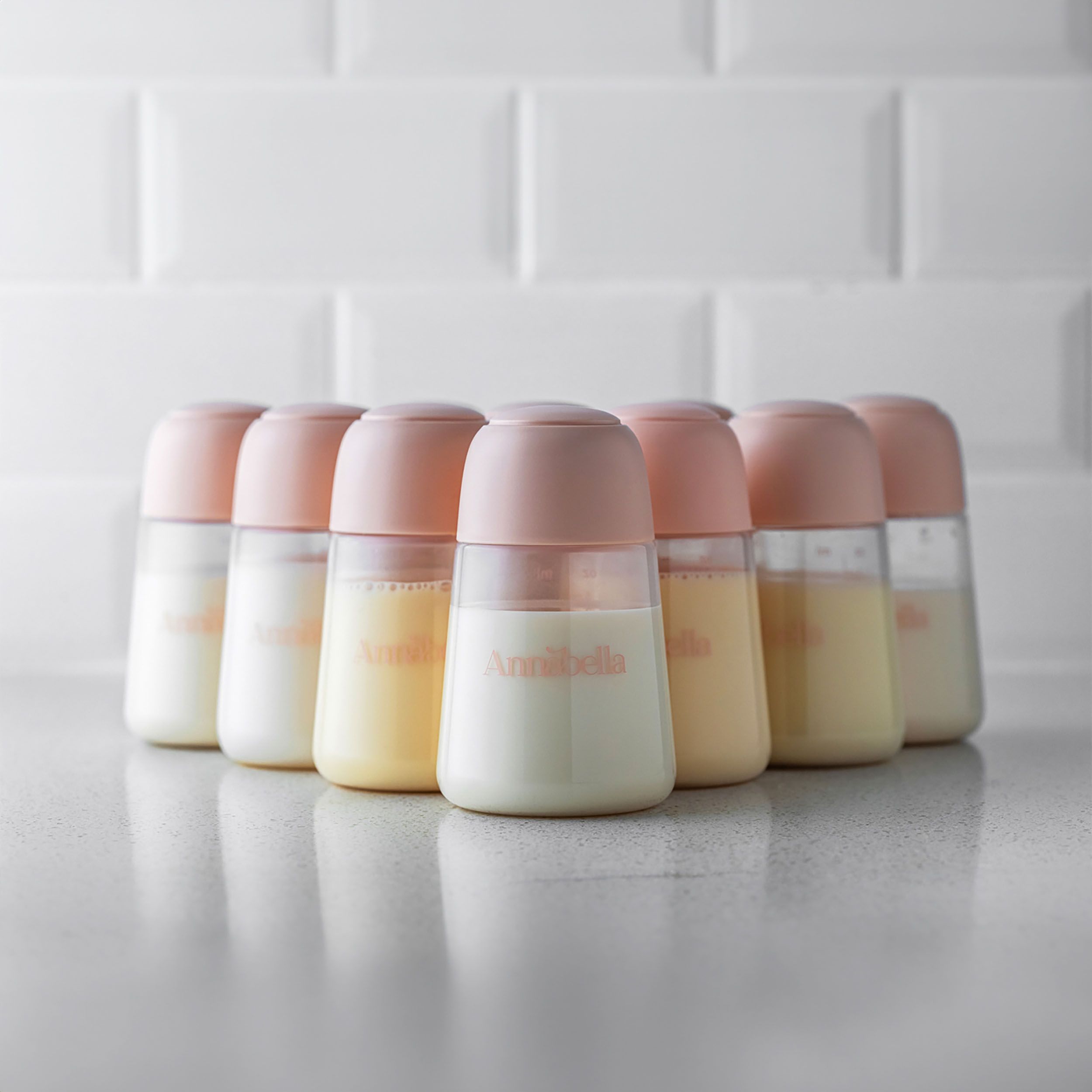 Acht Flaschen mit Deckeln, gefüllt mit Milch. Skala und Logo "Annabella" sichtbar. Auf einer Oberfläche platziert.