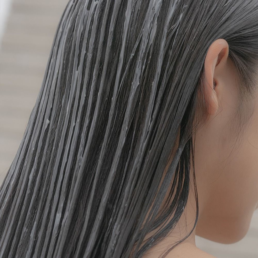 Person mit Maske auf dem Haar. Haare mit Produkt bedeckt. Nahaufnahme von hinten.