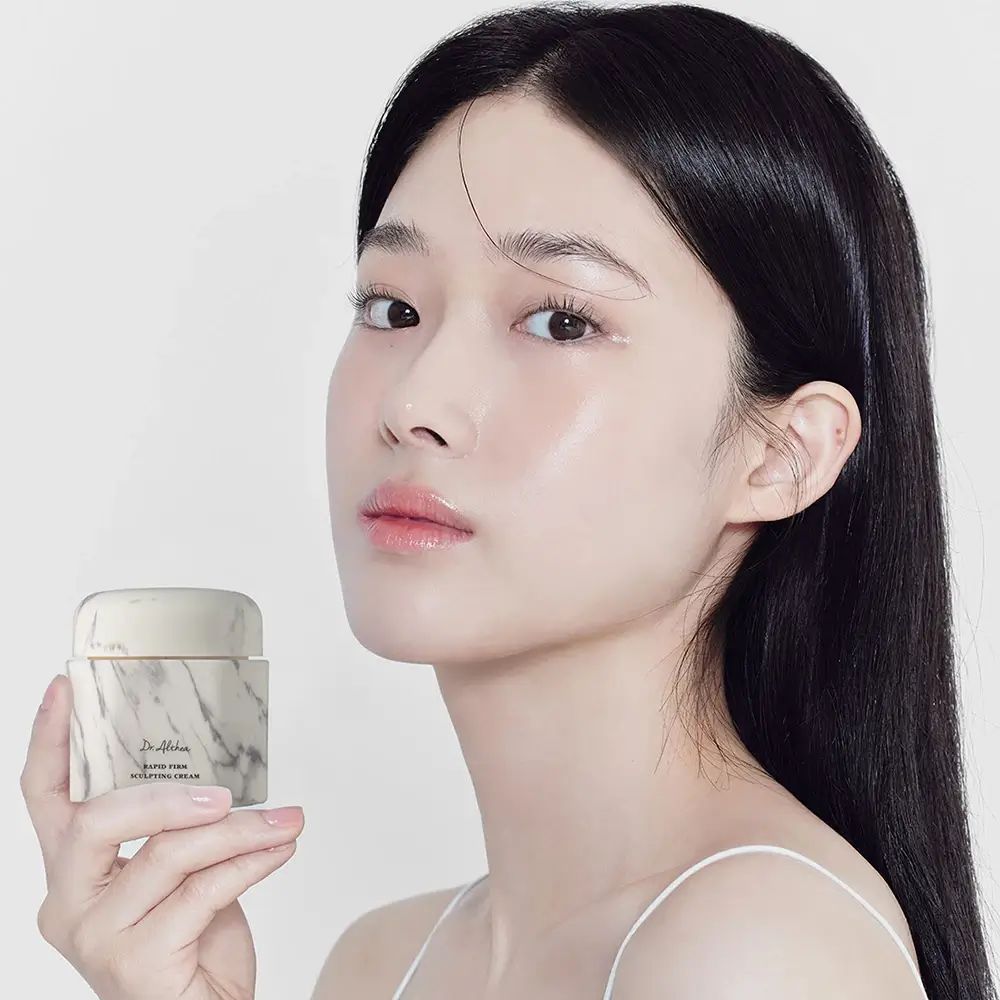 Frau hält einen Cremebehälter mit Marmor-Optik. Aufschrift: Dr. Althea, Rapid Firm Sculpting Cream.