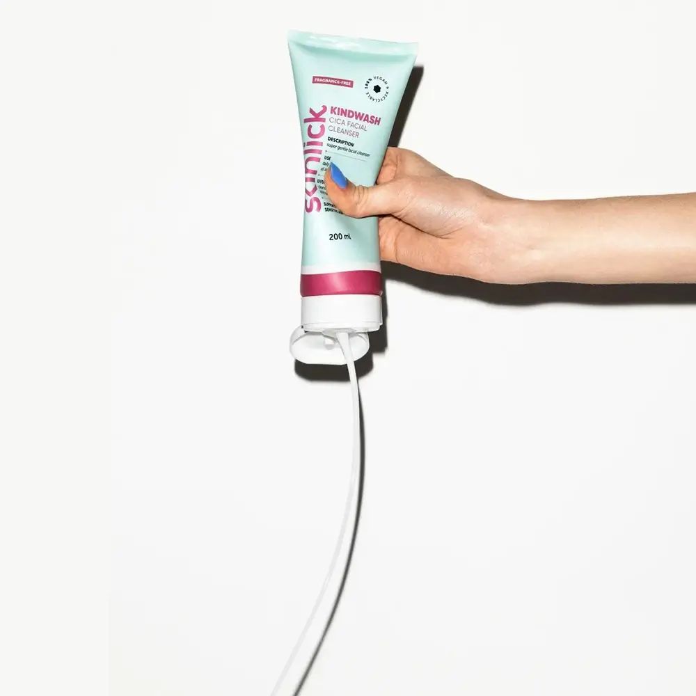 Hellgrüne Tube mit pinkfarbenem Streifen. Text: Kindwash, Cica Facial Cleanser. Produkt wird von Hand gehalten. Weißer Hintergrund.