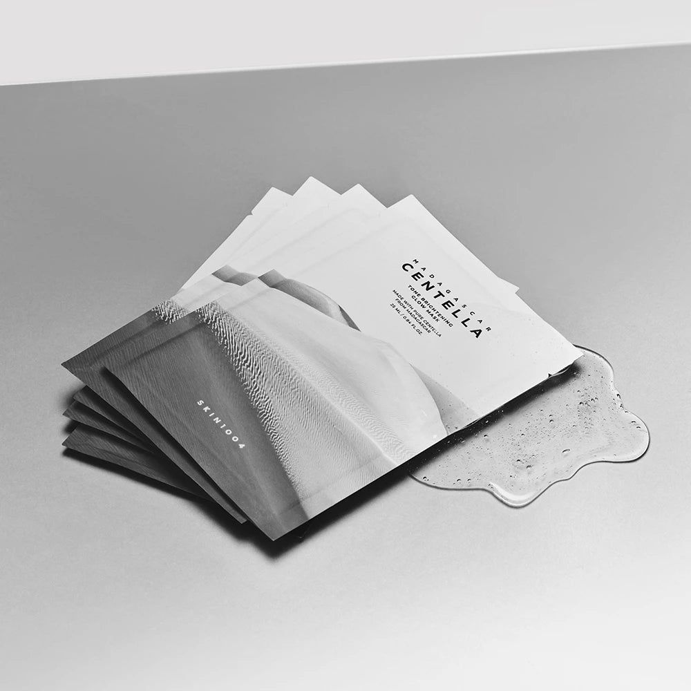 Mehrere Maskenbeutel mit Text und Bild. Daneben eine kleine Menge Gel. Aufschrift: MADAGASCAR CENTELLA. Marke: SKIN1004.