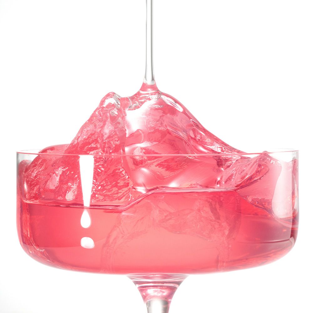 Rosa Flüssigkeit mit Eiswürfeln in einem Glas.