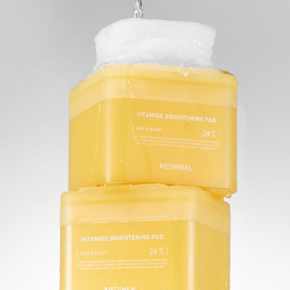 Zwei gelbe Dosen mit der Aufschrift Vitamide Brightening Pad. Wasser fließt auf die obere Dose.