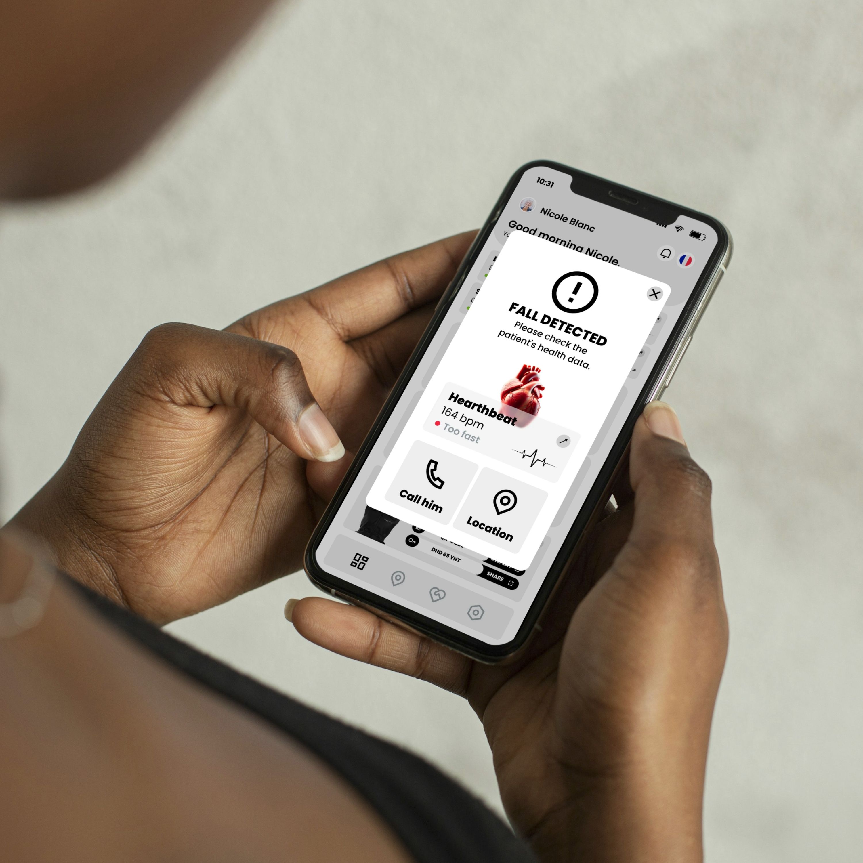 Person hält Smartphone mit Benutzeroberfläche. Meldung: "FALL DETECTED". Herzfrequenz: 164 bpm. Optionen: Anrufen, Standort.