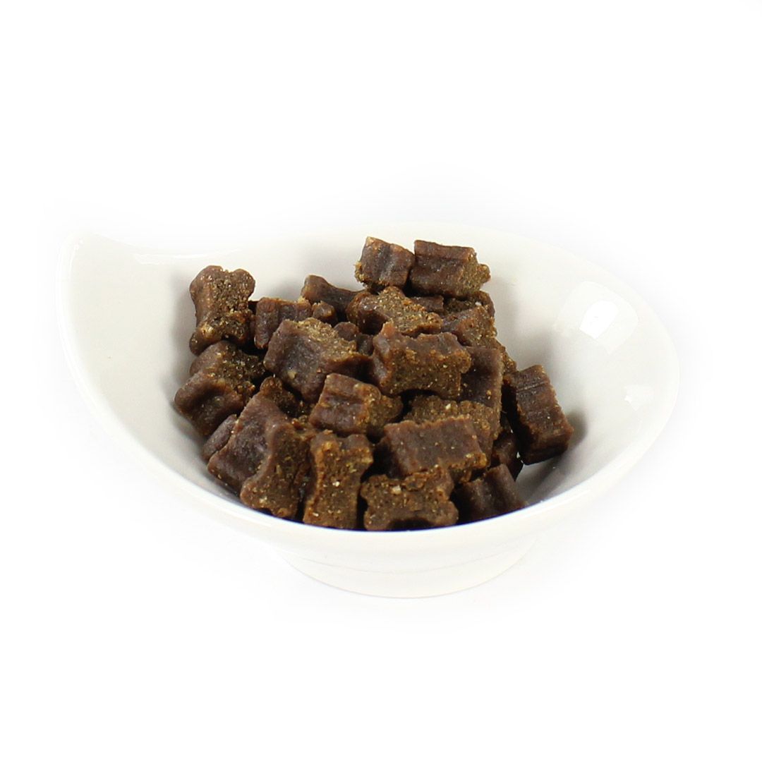Hundefutter-Snacks in einer weißen Schale. Die Snacks sind braun und in Würfelform.