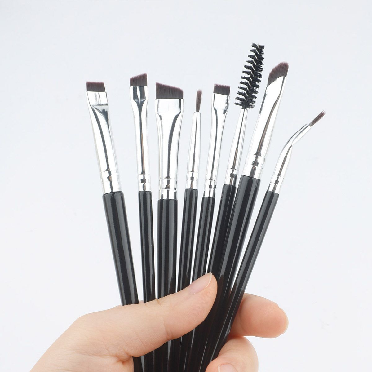 Ein Satz von acht schwarzen Make-up-Pinseln mit silbernen Griffen und verschiedenen Borstenformen.