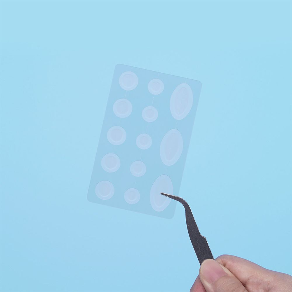 Transparente Pflaster auf einem Blatt. Eine Pinzette hält ein Pflaster. Blauer Hintergrund.