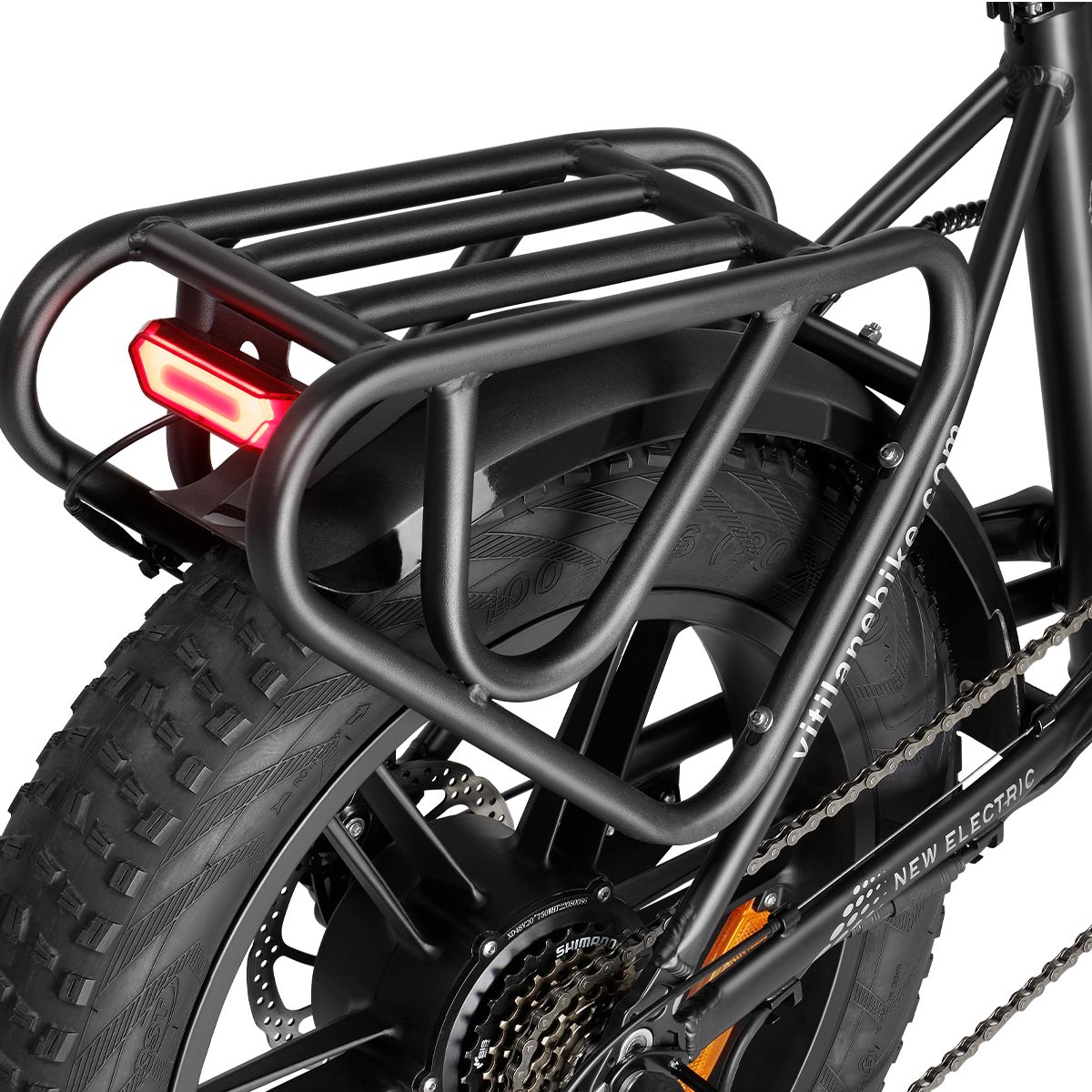 Schwarzer Gepäckträger mit Rücklicht an einem E-Bike. Kotflügel und Teile des Hinterrads sind sichtbar.