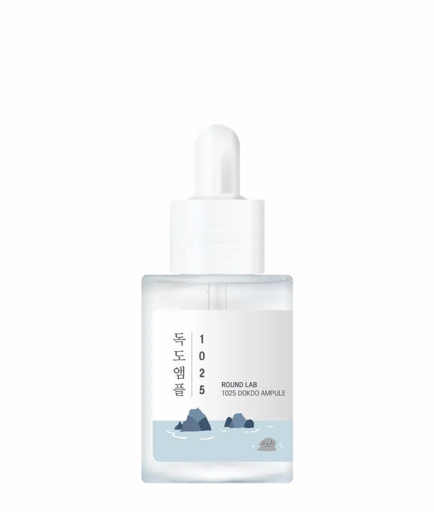 Klarer Glasflakon mit weißem Deckel und Pipette. Aufkleber mit Text und Illustrationen. Produktname: Round Lab 1025 Dokdo Ampoule.