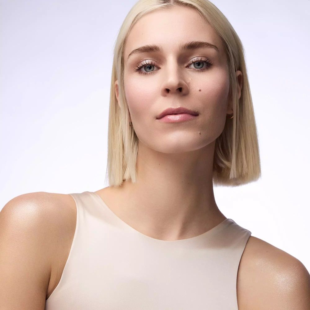 Porträt einer Frau mit blonden Haaren und hellem Oberteil. Blick nach vorne.