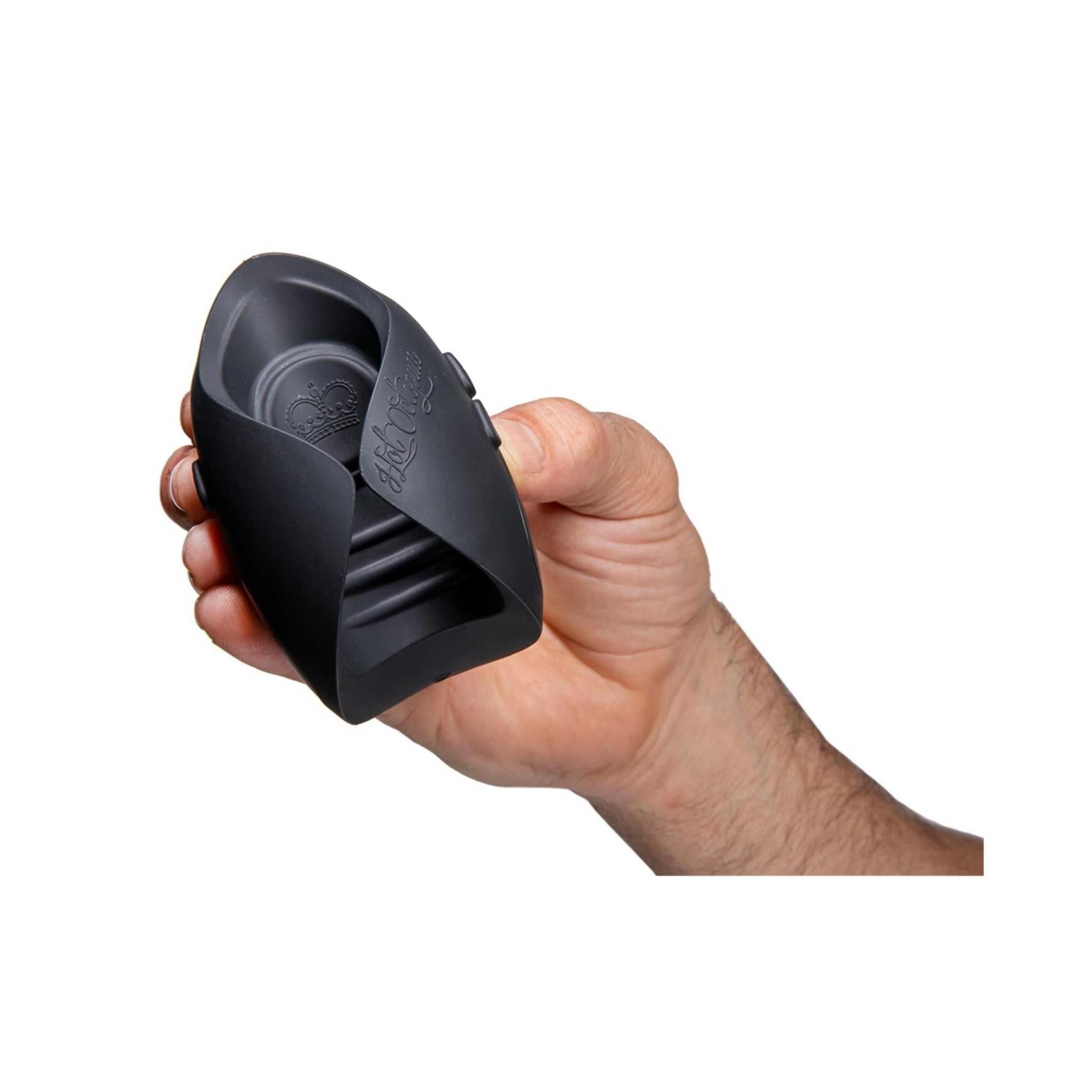 Dunkelgraues Produkt, in einer Hand gehalten. Ovale Form mit zwei seitlichen Flügeln. Zwei Knöpfe.