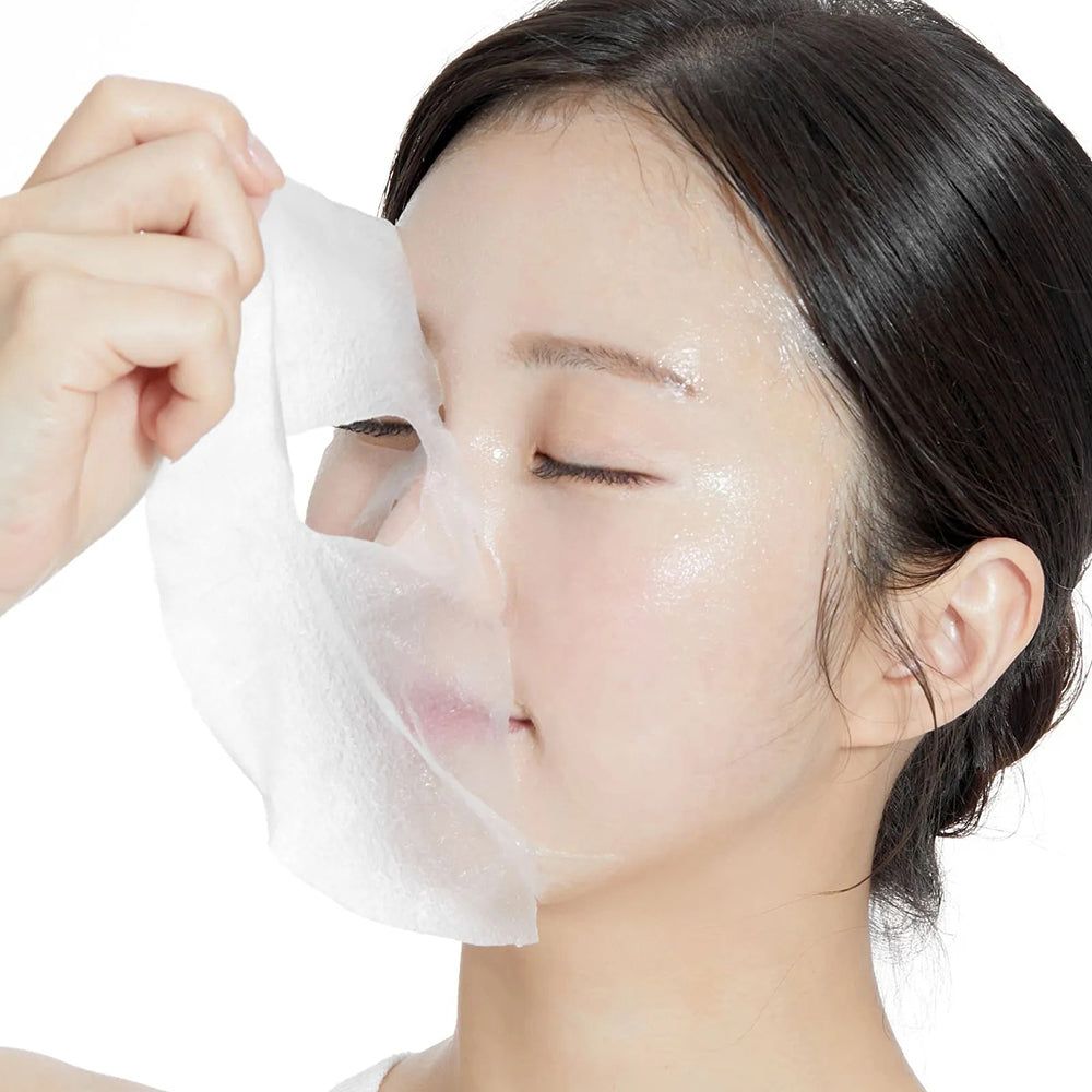 Gesichtsmaske wird auf Gesicht aufgetragen. Weiße Maske, Frau hält Maske. Hautpflegeprodukt.