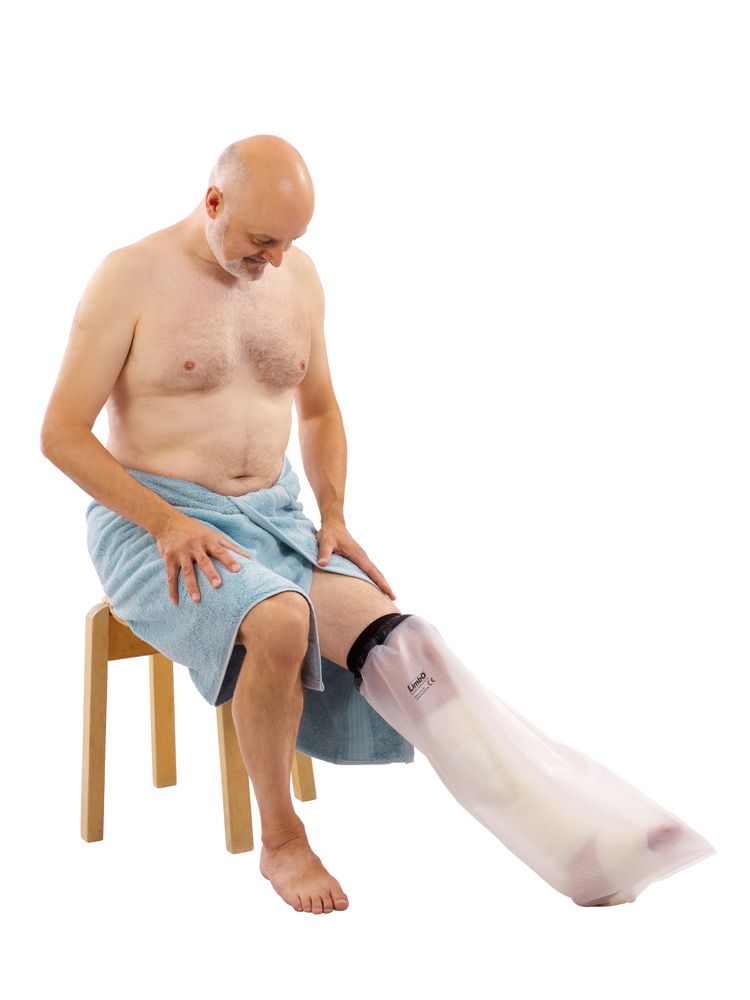Beinschutz für Gipsverbände. Transparente Hülle, schwarzer Abschluss. Mann sitzt auf Hocker, Bein geschützt.