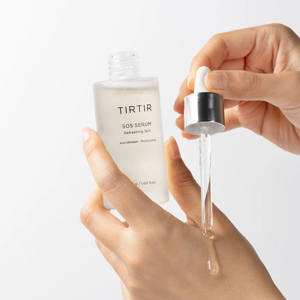 Hände halten Serumflasche und Pipette. Aufschrift: TIRTIR SOS Serum. Tropfen Serum auf Hand.