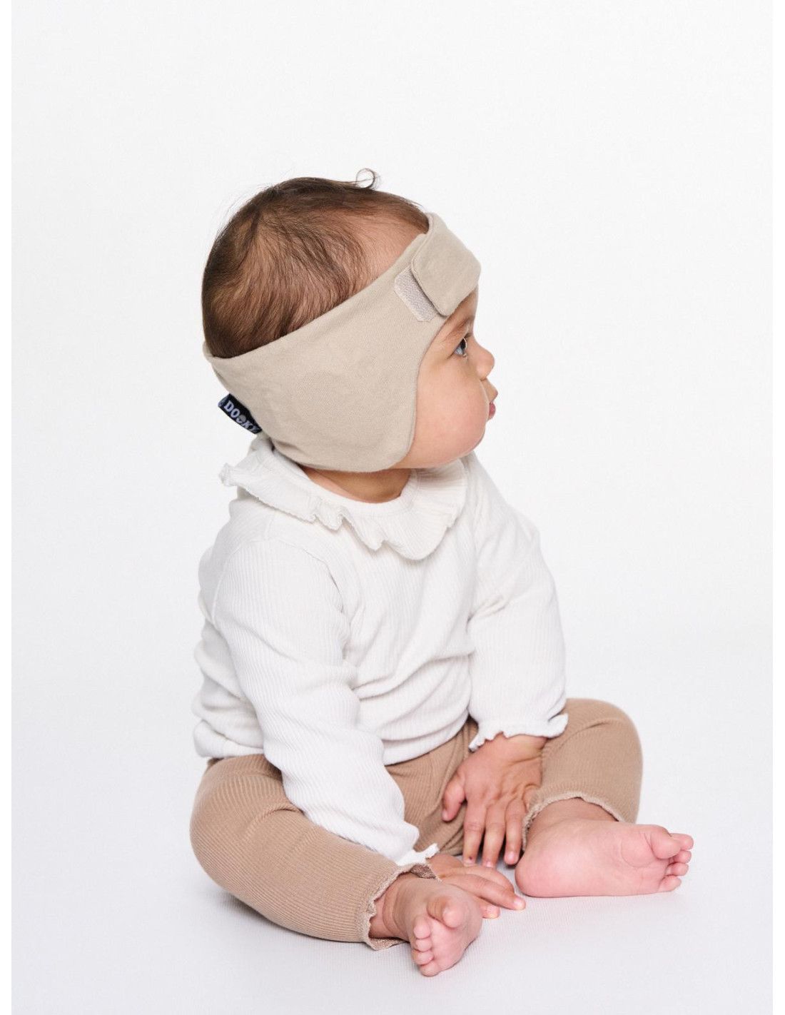 Baby mit beigem Kopfband, das mit einem Muster verziert ist.