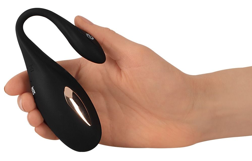 Schwarzes, gebogenes Produkt in einer Hand gehalten. Goldfarbener Akzent und Knopf sichtbar.