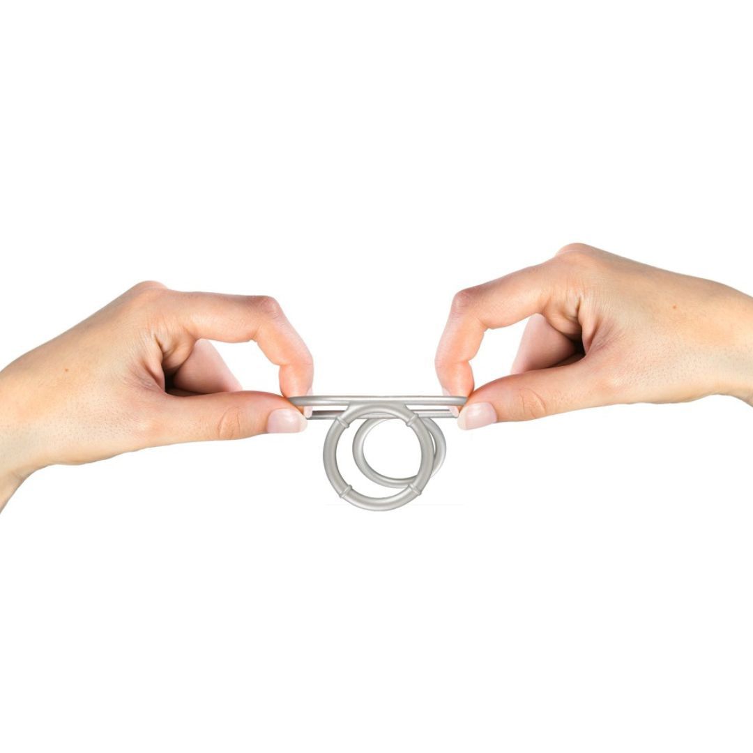 Zwei Hände halten einen silberfarbenen Ring mit drei Öffnungen. Weißer Hintergrund.