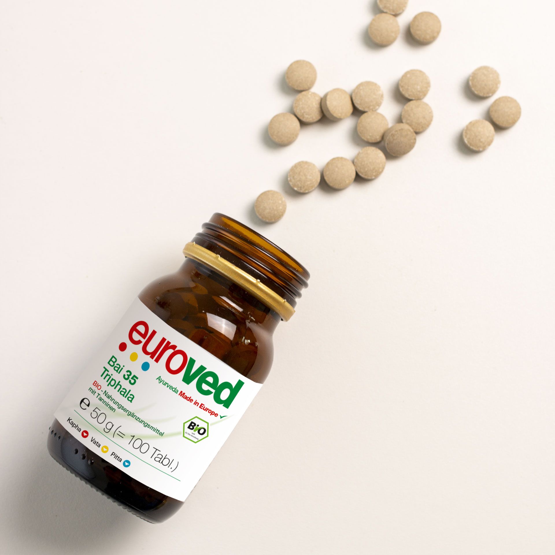 Braune Glasflasche mit goldfarbenem Deckel, Etikett mit Produktnamen und Bio-Siegel. Tabletten daneben.