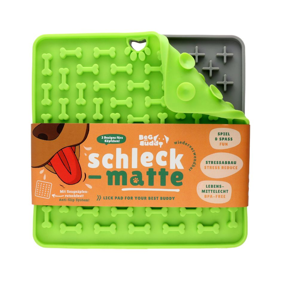 Grüne Leckmatte mit Knochenmuster und Aufkleber. Text: "Schleck-matte". Verpackt mit Band. Anti-Rutsch-System.
