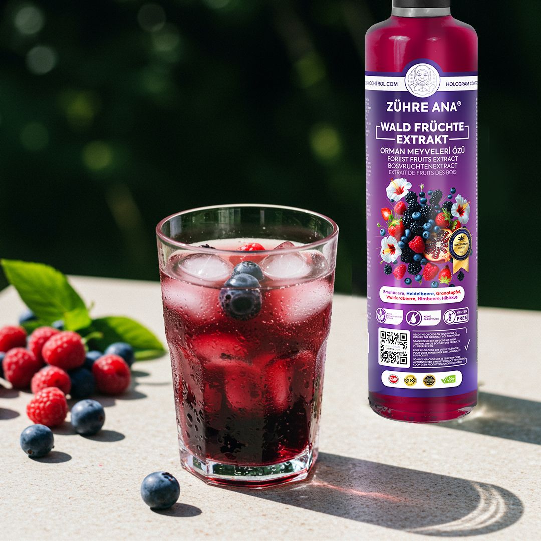Flasche mit Waldfrüchte-Extrakt neben einem Glas mit dunklem Getränk, Eis und Beeren.