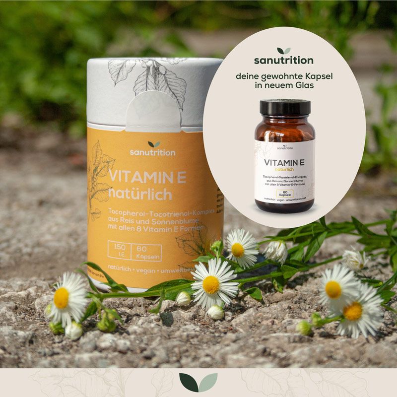 Zylinderförmige Dose und Flasche mit Sanutrition Vitamin E. Aufschrift: Vitamin E natürlich. Mit Blüten und Blättern dekoriert.
