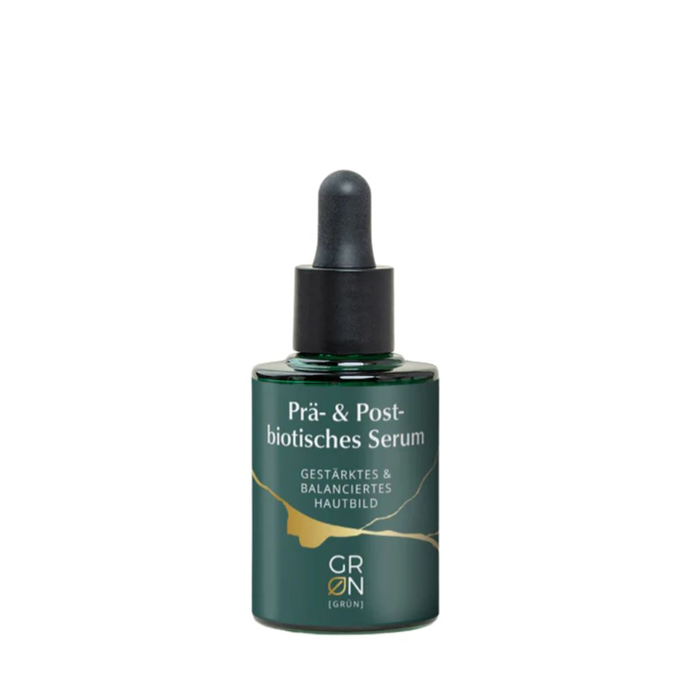 Grüne Serumflasche mit schwarzer Pipette. Aufschrift: Prä- & Postbiotisches Serum. Goldene Akzente.