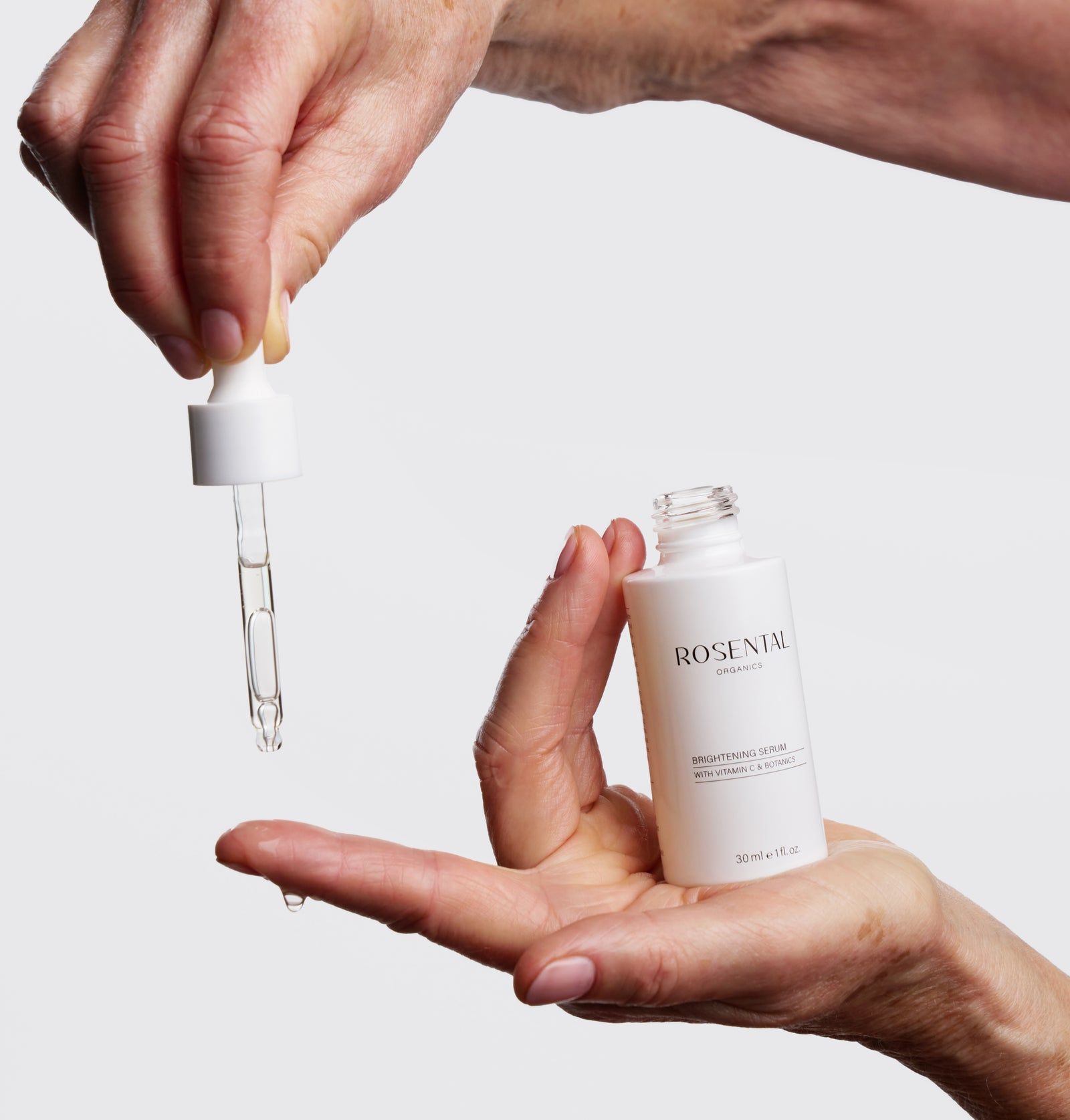 Hände halten eine Flasche und eine Pipette. Tropfen Serum fallen aus der Pipette.