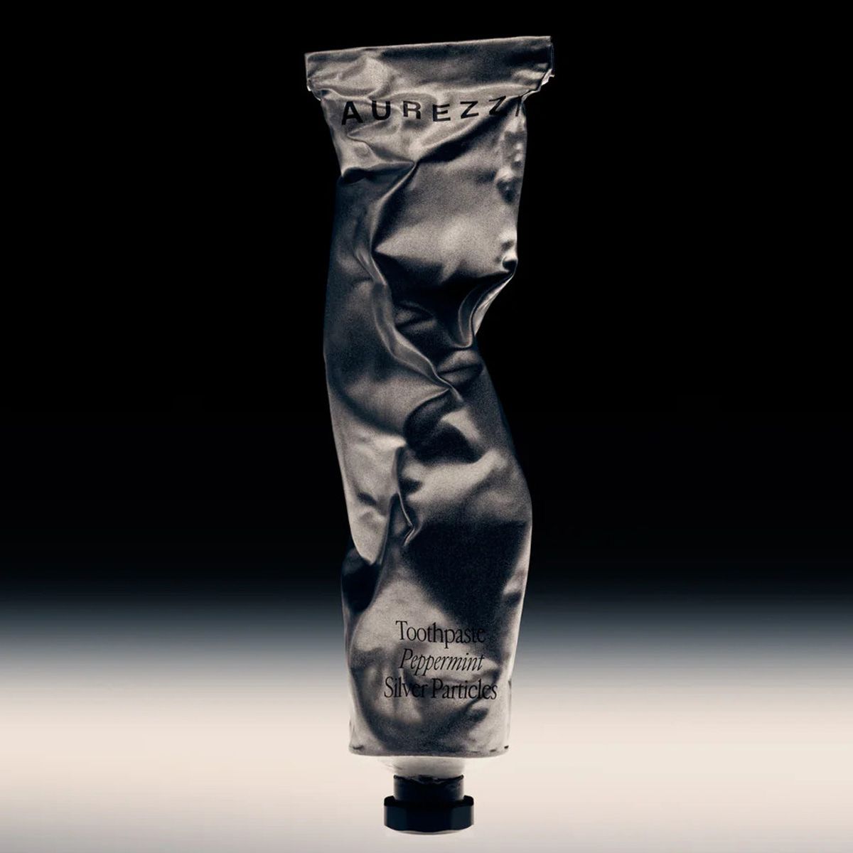 Zahnpasta-Tube, zerknittert. Aufschrift: AUREZZI. Aufschrift: Toothpaste Peppermint Silver Particles. Schwarzer Verschluss.