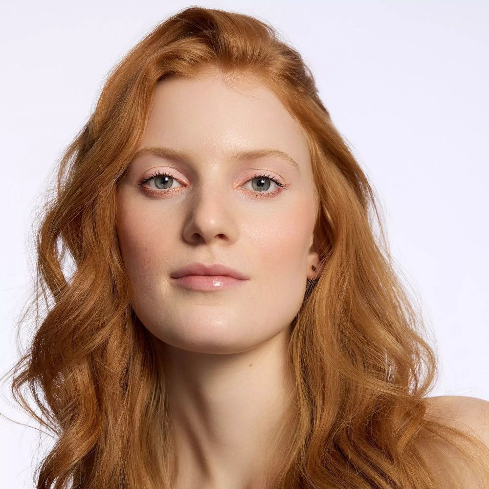 Porträt einer Frau mit roten Haaren. Sie hat helle Haut und blaue Augen. Sie trägt kein Make-up.