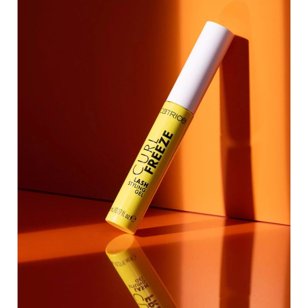 Gel-Tube, schräg stehend. Gelbe Tube mit schwarzem Schriftzug: CATRICE, CURL FREEZE, LASH STYLING GEL. 8 ml. Reflektion.