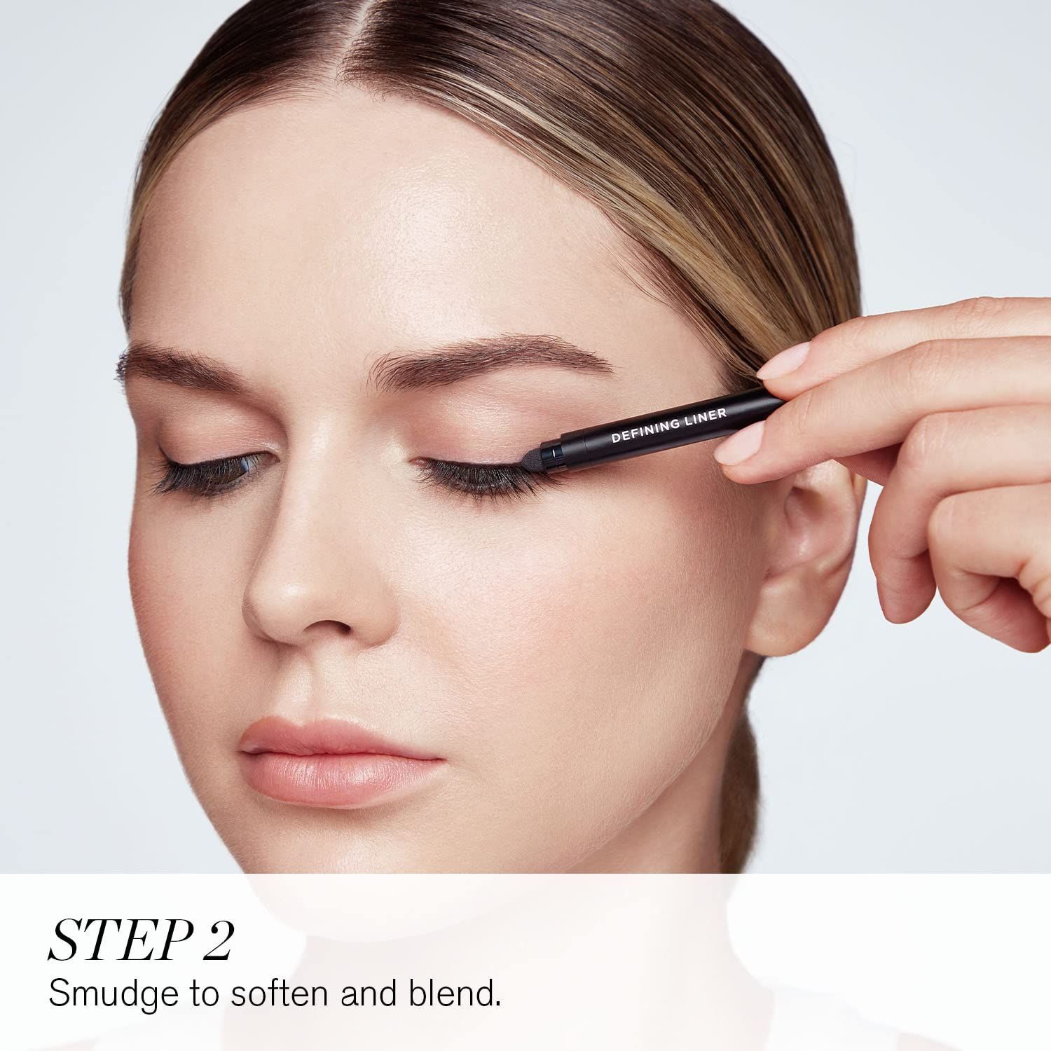 Frau trägt Eyeliner auf. Nahaufnahme einer Frau, die Eyeliner auf das obere Augenlid aufträgt. Text: STEP 2.