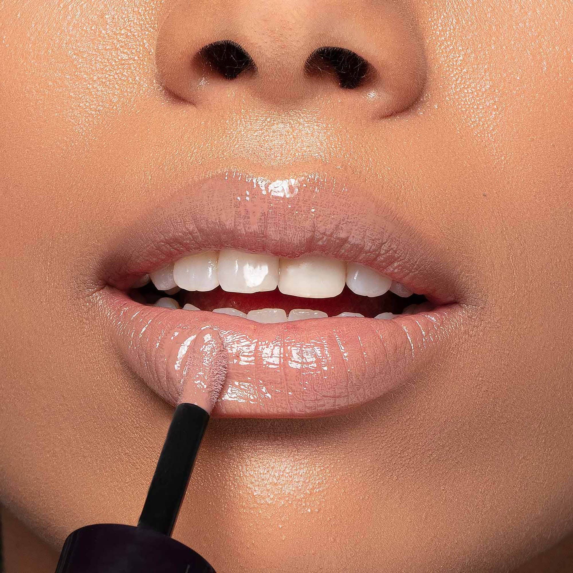 Lippen mit aufgetragenem Lipgloss. Der Applikator ist sichtbar. Glänzendes Finish.