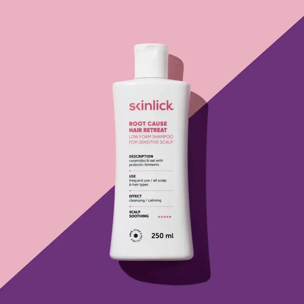 Weiße Shampoo-Flasche mit rosa und lila Hintergrund. Aufschrift: SKINLICK, ROOT CAUSE HAIR RETREAT, 250 ml.