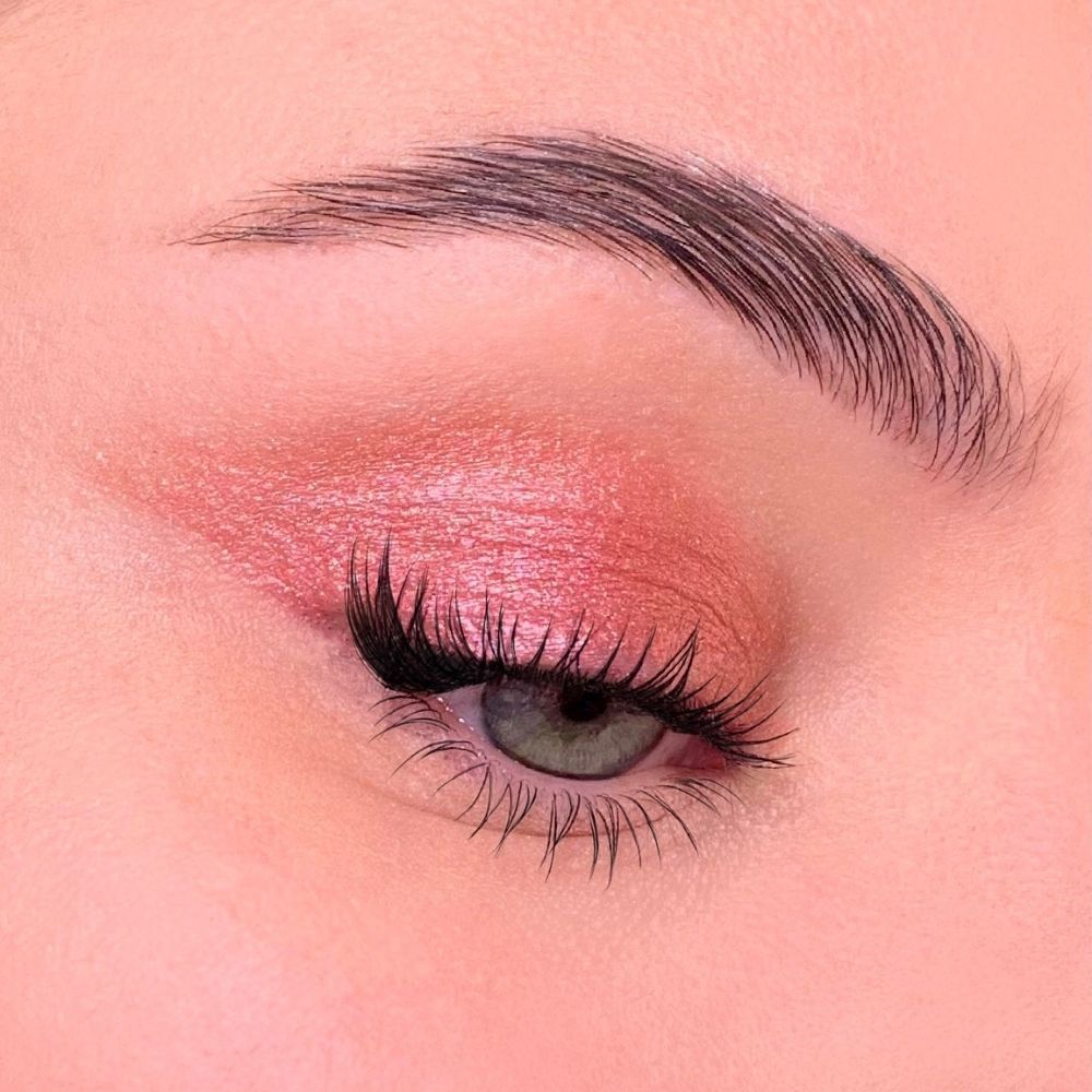 Auge mit rosafarbenem Lidschatten. Lange Wimpern, Augenbraue. Hautton.