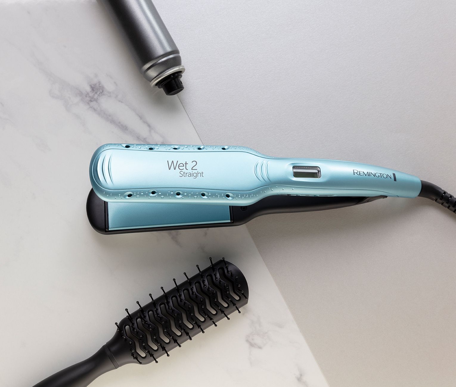 Hellblauer Haarglätter mit Bürste und Haarspray auf Marmoroberfläche.