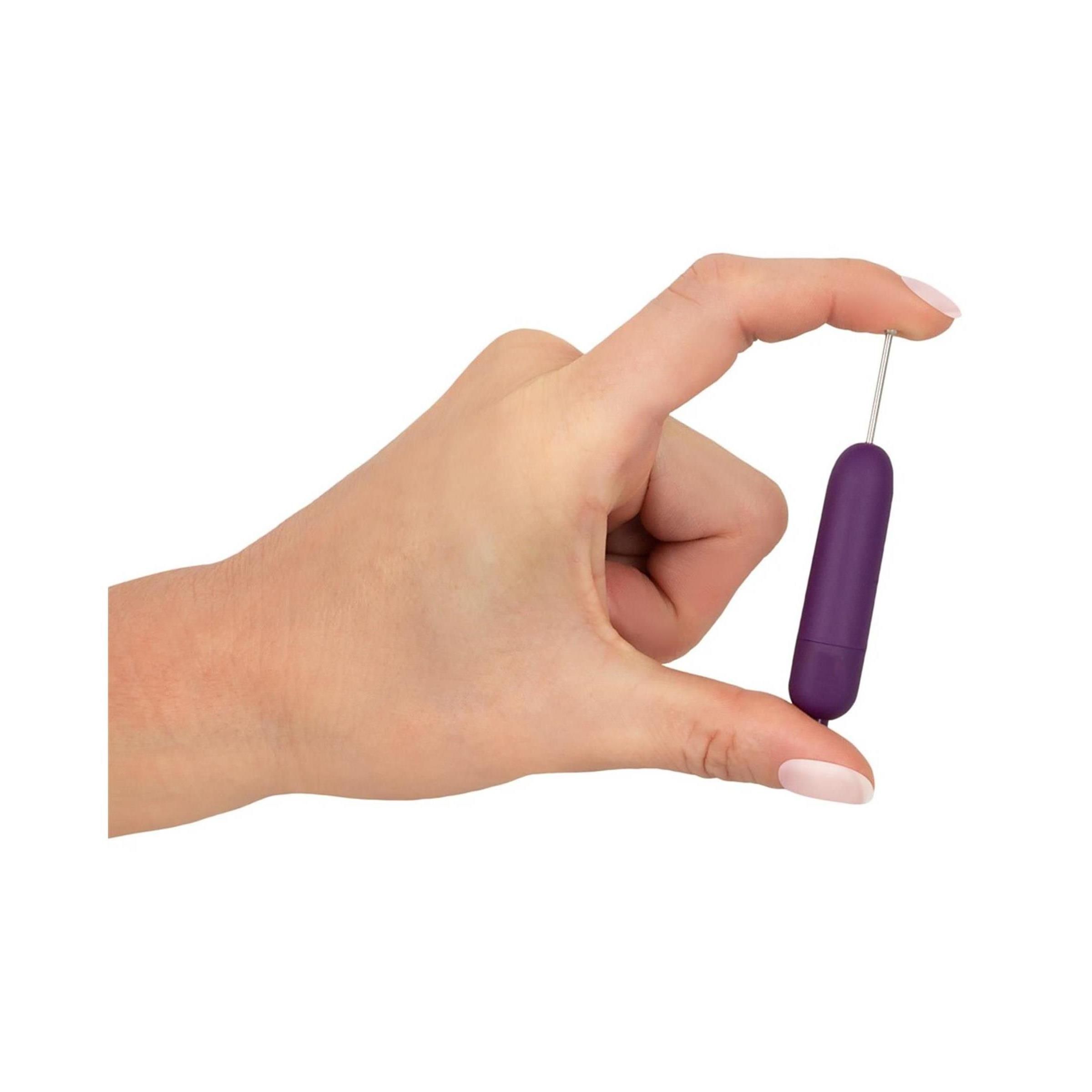 Hand hält lila Vibrator mit silbernem Stab und Kugel. Auf weißem Hintergrund.