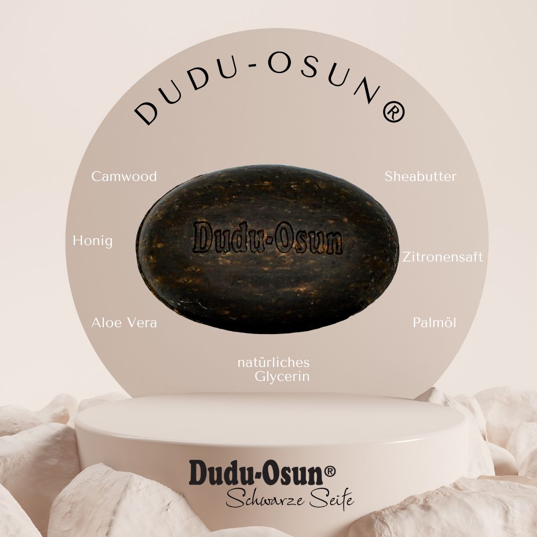 Schwarze Seife, oval, mit Prägung "Dudu-Osun". Auf Podest, umgeben von Zutaten-Namen: Camwood, Honig, Aloe Vera, Sheabutter, Zitronensaft, Palmöl, Glycerin.